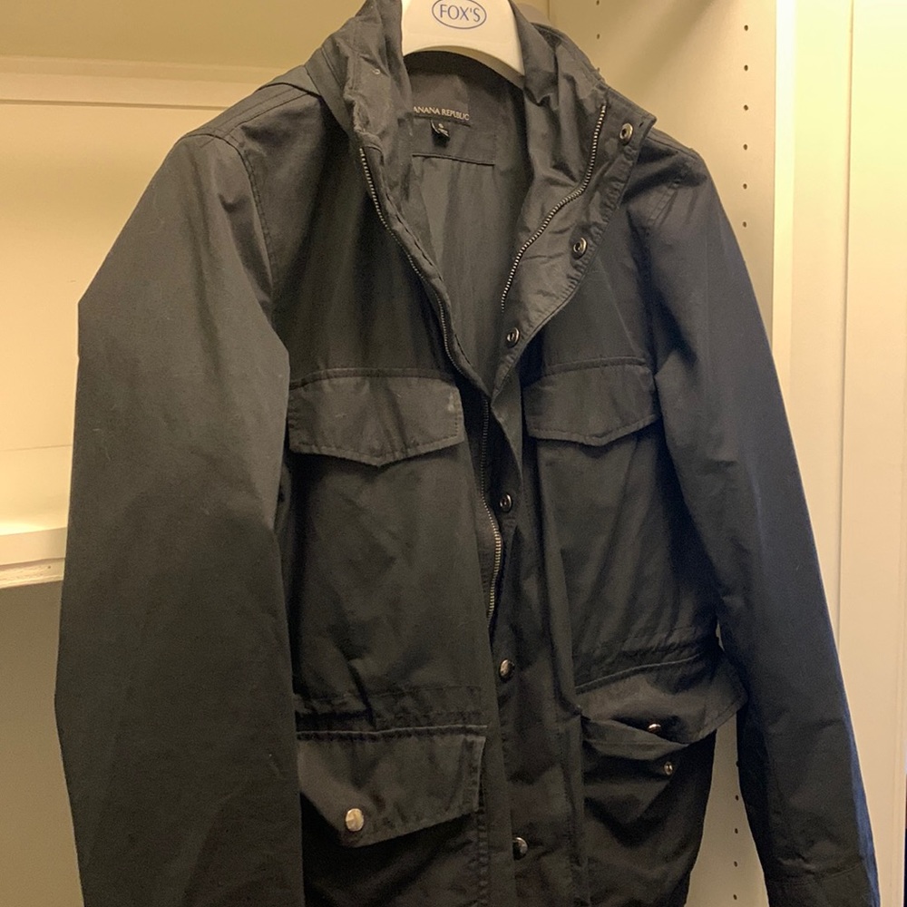 Black rain resistant jacket with hide-able roll up hood